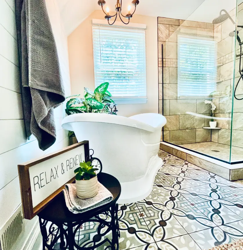 Bathroom with a white clawfoot tub, patterned tile floor, glass shower, and a "Relax & Renew" sign.