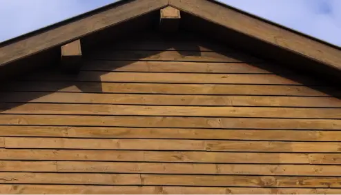Wooden gable of a house against a cloudy sky background.