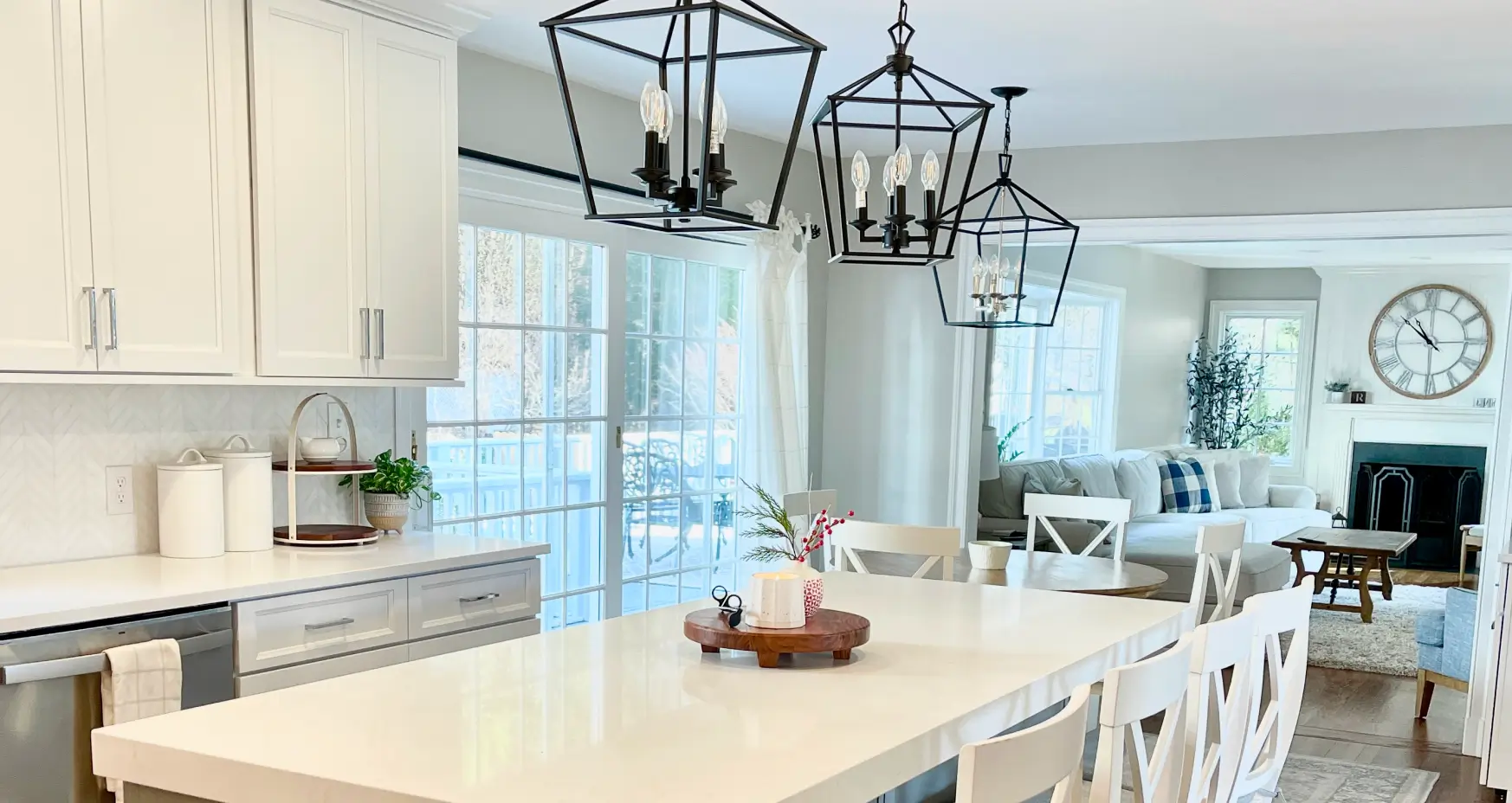 Bright kitchen and living area with white cabinets, island, and modern pendant lights.