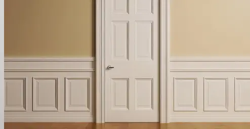 A white paneled door set in light-colored walls with decorative wainscoting, next to a hardwood floor.