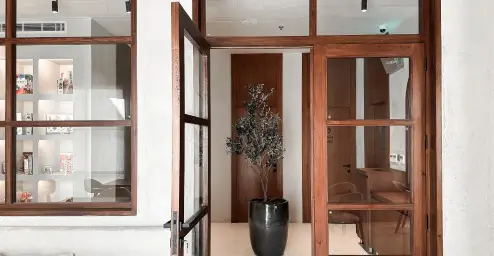 Open glass door in a modern room with a potted plant, wooden accents, and minimal decor.