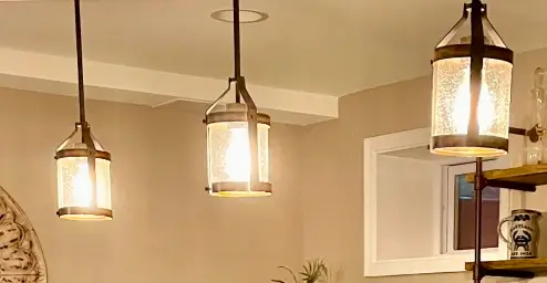 Hanging lantern-style light fixtures in a warmly lit room with a small window.